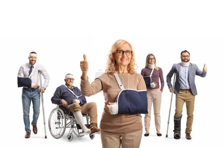Foto de Paciente femenina con lesión en el brazo y un grupo de personas con muletas y una silla de ruedas de pie en la espalda aislada sobre fondo blanco - Imagen libre de derechos
