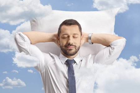 Téléchargez les photos : Portrait d'un homme d'affaires reposant sur un oreiller en chemise et cravate dans le ciel - en image libre de droit