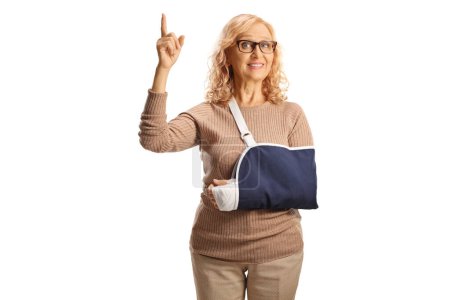 Photo for Woman with injured arm wearing a sling and pointing up isolated on white background - Royalty Free Image