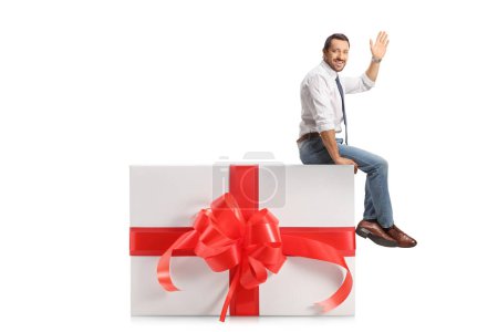 Foto de Empresario sentado en una gran caja de regalo y saludando aislado sobre fondo blanco - Imagen libre de derechos
