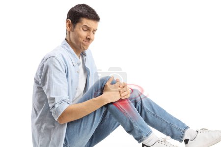 Photo for Young man sitting on the floor and holding his knee in pain, bone inflammation with red, isolated on white background - Royalty Free Image