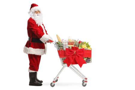 Photo for Full length shot of Santa Claus with a shopping cart tied with a red bow isolated on white background - Royalty Free Image