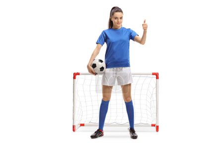 Photo for Full length portrait of a female soccer player making a thumb up sign in front of a mini goal isolated on white background - Royalty Free Image