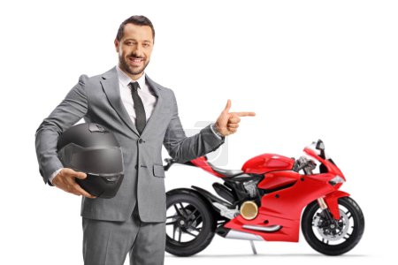 Photo for Businessman holding a helmet and pointing at a red motorbike isolated on white background - Royalty Free Image