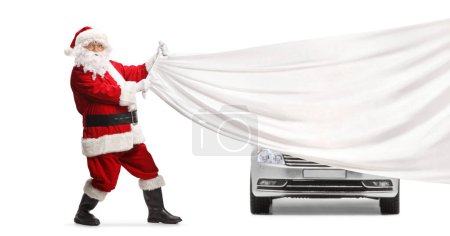 Foto de Santa Claus tirando de un trozo blanco de tela delante de un coche plateado aislado sobre fondo blanco - Imagen libre de derechos