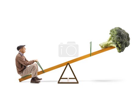 Photo for Full length profile shot of an elderly man and a broccoli on a seesaw isolated on white background - Royalty Free Image