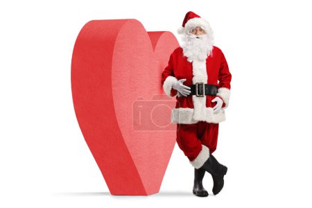 Téléchargez les photos : Portrait complet du Père Noël appuyé sur un cœur rouge isolé sur fond blanc - en image libre de droit