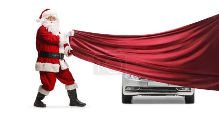 Photo for Santa Claus pulling a red piece of cloth in front of a new car isolated on white background - Royalty Free Image