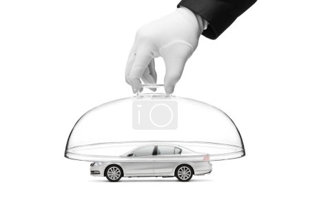 Téléchargez les photos : Une main gantée mettant un dôme de verre sur une voiture symbolisant la sécurité automobile et le concept d'assurance automobile isolé sur fond blanc - en image libre de droit