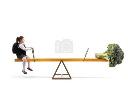 Téléchargez les photos : Image de profil pleine longueur d'une écolière et d'un légume brocoli sur une balançoire, concept d'alimentation saine isolé sur fond blanc - en image libre de droit