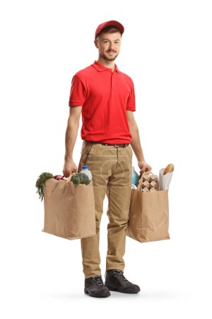Photo for Full length shot of a delivery guy holding bags with groceries isolated on white background - Royalty Free Image