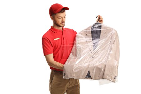 Téléchargez les photos : Travailleur de nettoyage à sec tenant une combinaison avec une housse de sac en plastique isolé sur un dosseret blanc - en image libre de droit