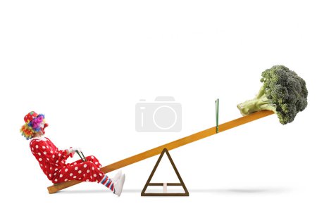 Photo for Clown with a broccoli vegetable on a seesaw, healthy diet concept isolated on white background - Royalty Free Image
