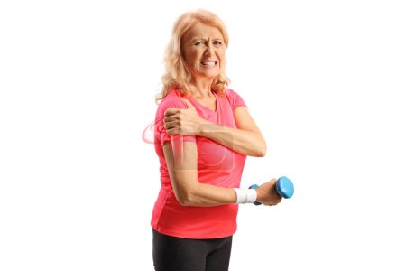 Téléchargez les photos : Femme en tenue de sport avec épaule douloureuse tenant un haltère et regardant la caméra isolée sur fond blanc - en image libre de droit