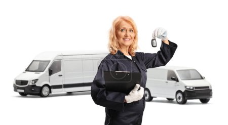 Photo for Female mechanic worker in a uniform holding a clipboard and a key in front of vans isolated on white background - Royalty Free Image