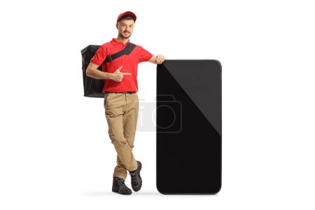 Photo for Delivery man leaning on a smartphone and pointing isolated on white background - Royalty Free Image