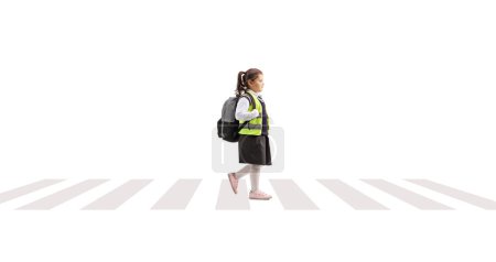 Téléchargez les photos : Profil complet d'une écolière portant un gilet de sécurité et traversant une rue isolée sur fond blanc - en image libre de droit