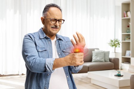 Téléchargez les photos : Homme mûr souffrant d'arthrite et tenant son poignet douloureux avec une inflammation rouge et jaune - en image libre de droit