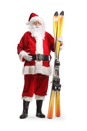 Foto de Retrato completo de Santa Claus sosteniendo un par de esquís aislados sobre fondo blanco - Imagen libre de derechos