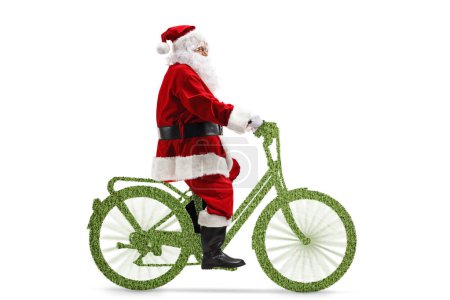 Foto de Foto de perfil completo de Santa Claus montando una bicicleta verde aislada sobre fondo blanco, concepto de movilidad sostenible - Imagen libre de derechos