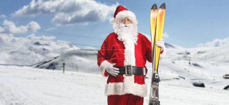 Foto de Santa Claus sosteniendo un par de esquís en una colina - Imagen libre de derechos