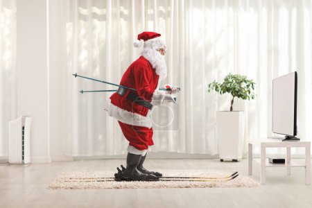Foto de Santa Claus esquiando en casa delante de la televisión - Imagen libre de derechos