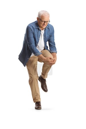 Photo for Mature man standing and bending his painful knee isolated on white background - Royalty Free Image