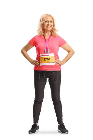 Foto de Retrato completo de una mujer corredora de maratón con un babero de carrera y una medalla sonriendo a la cámara aislada sobre fondo blanco - Imagen libre de derechos