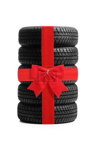 Téléchargez les photos : Plan studio d'une pile de pneus de véhicule avec ruban rouge arc isolé sur fond blanc - en image libre de droit