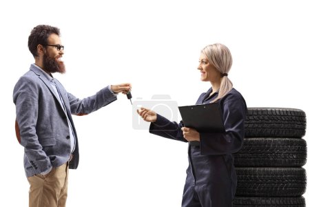 Photo for Man handing car keys to a female auto mechanic isolated on white background - Royalty Free Image