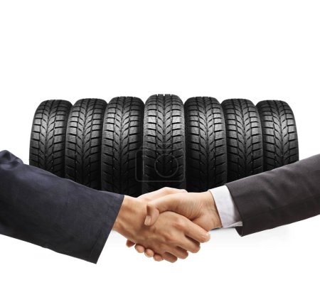 Foto de Auto mecánico y un hombre de negocios estrechando las manos frente a los neumáticos aislados sobre fondo blanco - Imagen libre de derechos