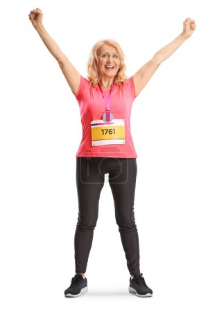 Foto de Retrato de larga duración de una corredora de maratón feliz con un babero de carrera y una medalla aislada sobre fondo blanco - Imagen libre de derechos