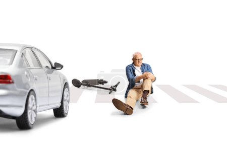 Photo for Man with an electric scooter holding injured knee and sitting on the street in front of a car isolated on white background - Royalty Free Image