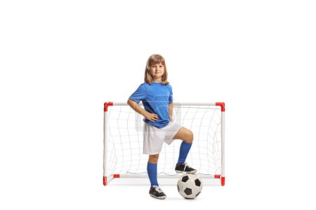 Photo for Girl in sports jersey standing with foot on top of a football in front of a goal net isolated on white background - Royalty Free Image