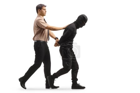 Foto de Guardia de seguridad caminando con ladrón detenido en ropa negra y pasamontañas aislados sobre fondo blanco - Imagen libre de derechos