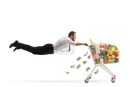 Foto de Hombre volando y sosteniendo un carro de compras con comida y dinero aislado sobre fondo blanco - Imagen libre de derechos