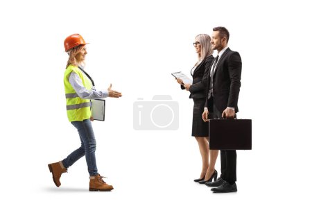Photo for Full length profile shot of a female engineer walking and greeting businesspeople isolated on white background - Royalty Free Image