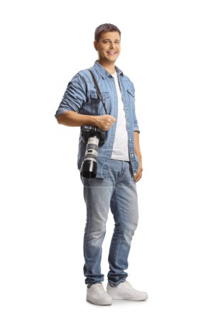 Téléchargez les photos : Portrait complet d'un photographe homme portant un appareil photo professionnel et souriant isolé sur fond blanc - en image libre de droit