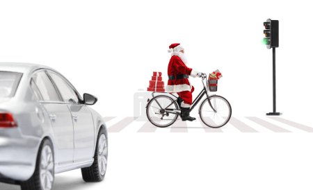 Téléchargez les photos : Photo de profil pleine longueur du Père Noël en vélo et traversant une rue isolée sur fond blanc - en image libre de droit