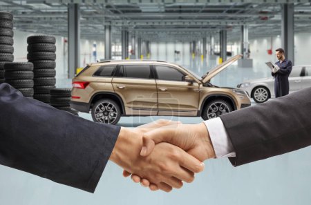 Photo for Men shaking hands inside a car repair garage - Royalty Free Image