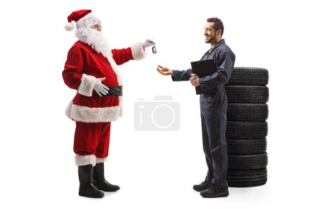 Foto de Perfil de longitud completa plano de Santa Claus dando llaves de coche a un mecánico aislado sobre fondo blanco - Imagen libre de derechos