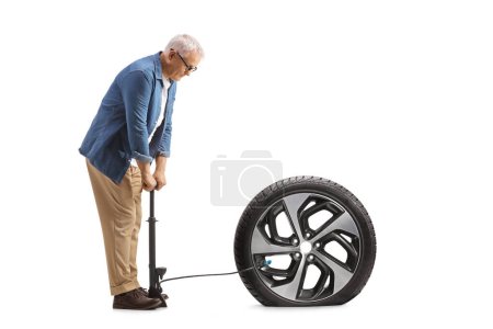 Téléchargez les photos : Homme mûr utilisant une pompe manuelle pour un pneu de voiture à plat isolé sur fond blanc - en image libre de droit