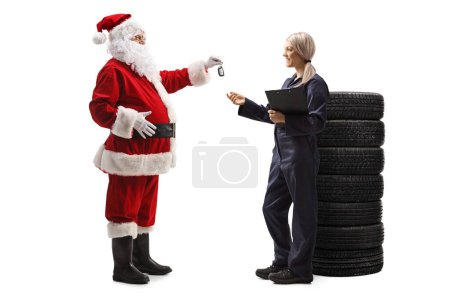 Téléchargez les photos : Plan de profil complet de Santa Claus donnant des clés de voiture à un mécanicien automobile féminin isolé sur fond blanc - en image libre de droit