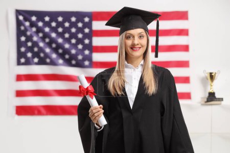 Téléchargez les photos : Étudiante diplômée avec un diplôme portant un chapeau de graduation avec drapeau des États-Unis en arrière-plan - en image libre de droit