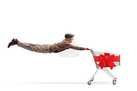 Téléchargez les photos : Plan complet d'un vieillard décontracté volant et tenant un chariot vide attaché avec un ruban rouge isolé sur fond blanc - en image libre de droit