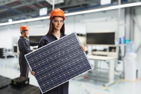 Foto de Producción de paneles solares, trabajadores dentro de una fábrica que sostiene fotovoltaica - Imagen libre de derechos