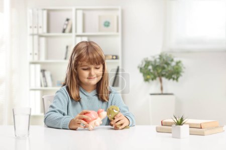 Téléchargez les photos : Petite fille mignonne assise à la maison et jouant avec des jouets animaux - en image libre de droit