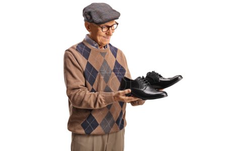 Photo for Elderly man holding a pair of black leather shoes and smiling isolated on white background - Royalty Free Image