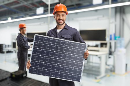 Photo for Worker in a uniform holding a solar panel inside a factory - Royalty Free Image