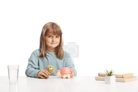Téléchargez les photos : Petite fille mignonne assise à une table et jouant avec des jouets d'animaux - en image libre de droit
